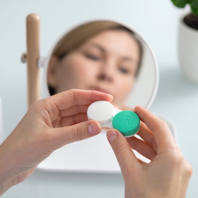A woman holds a contact lens container in her hands